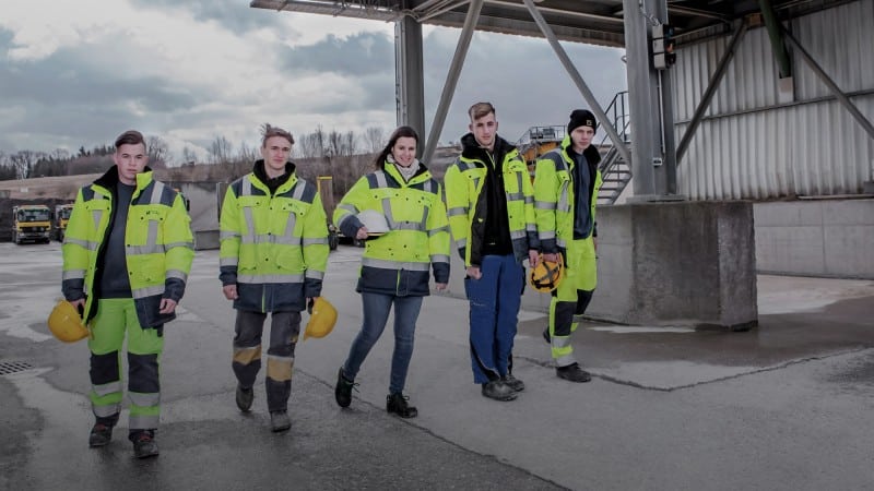 Fünf junge Menschen in signalgelber Arbeitskleidung auf Baustelle